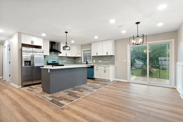 a kitchen with granite countertop a stove a sink dishwasher a refrigerator and white cabinets with wooden floor