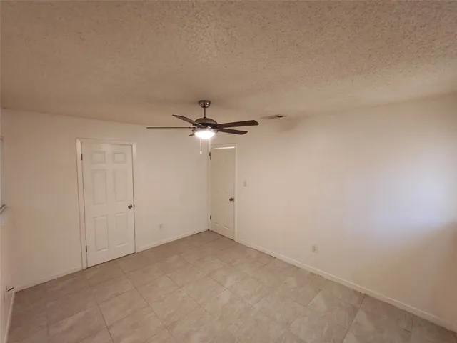 an empty room with a ceiling fan and a window