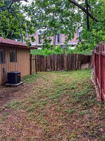a view of a backyard with wooden fence and a large tree