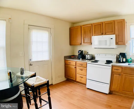 a kitchen with a stove a sink wooden floor and cabinets