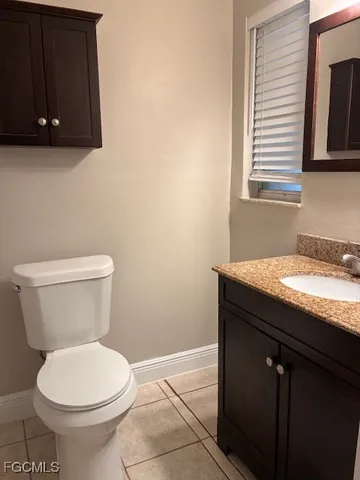 a bathroom with a granite countertop toilet sink and mirror