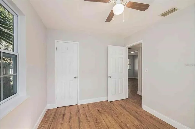 a view of empty room with wooden floor and fan