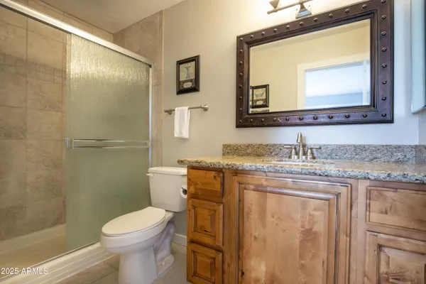 a bathroom with a granite countertop toilet sink and mirror