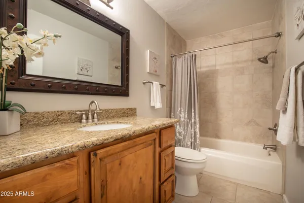 a bathroom with a granite countertop sink toilet mirror and bathtub