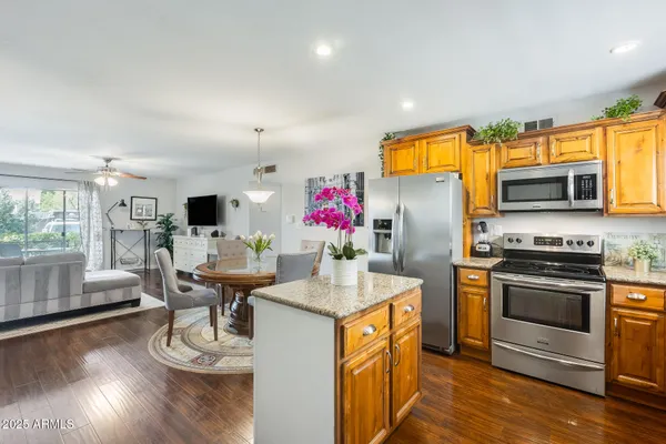 a kitchen with stainless steel appliances kitchen island granite countertop a stove and a wooden floor