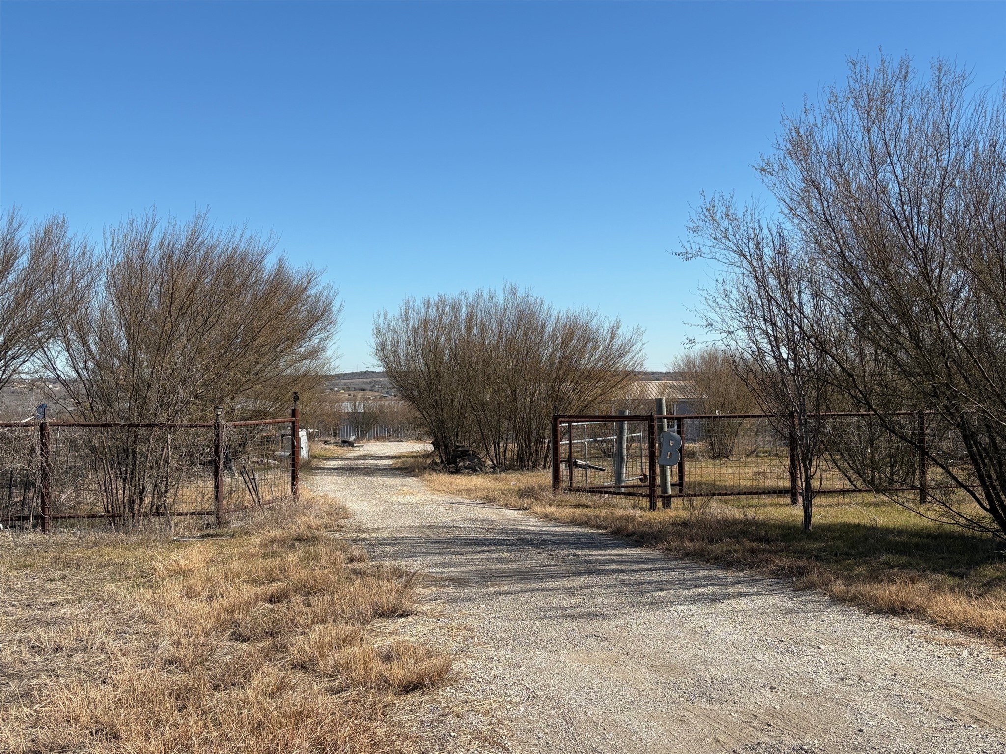 View of dirt / gravel road featuring a gate and a view of rural / pastoral area