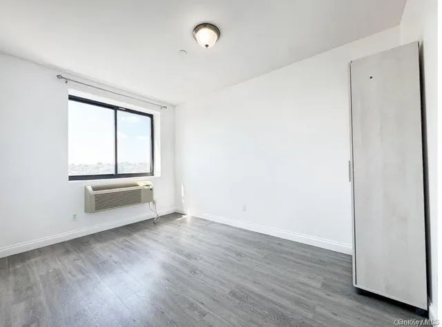 an empty room with wooden floor cabinet and windows