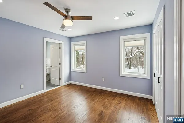 an empty room with wooden floor closet and windows