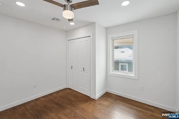 an empty room with wooden floor fan and windows