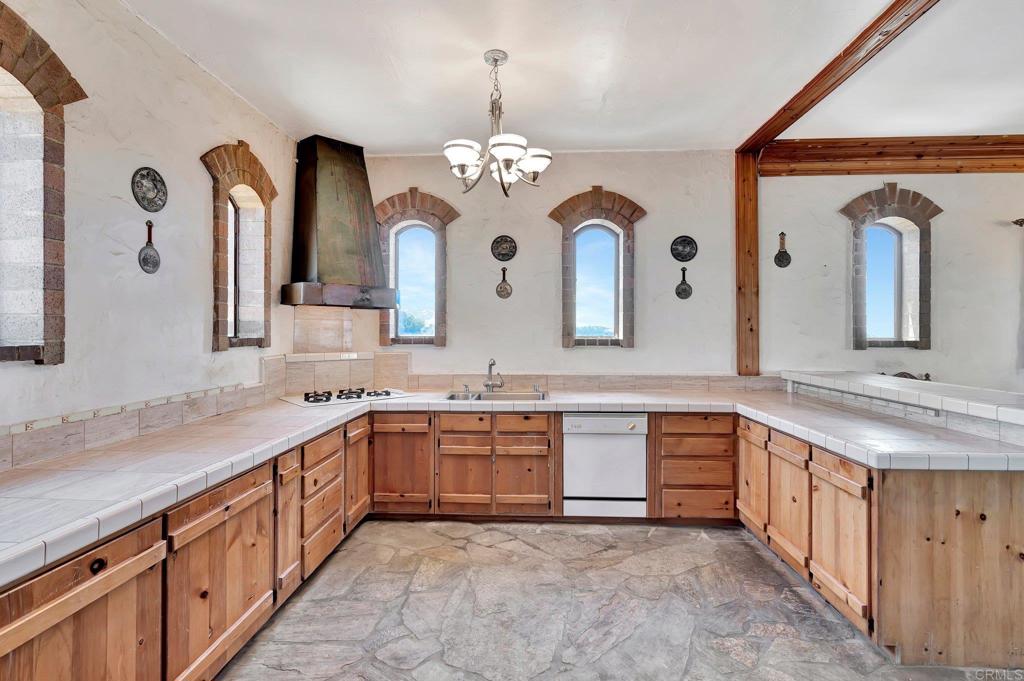 19105 Laminack Lane Jamul, CA 91935 - Photo 14 of 27 a large kitchen with stainless steel appliances granite countertop a sink dishwasher a dining table and chairs with wooden floor