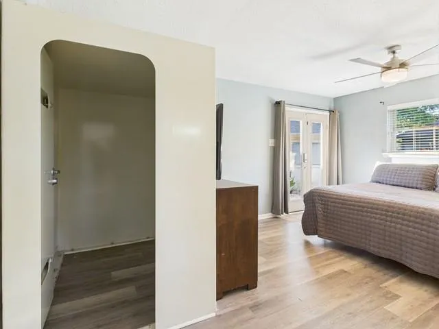 a bedroom with a bed window and walk in closet with wooden floor