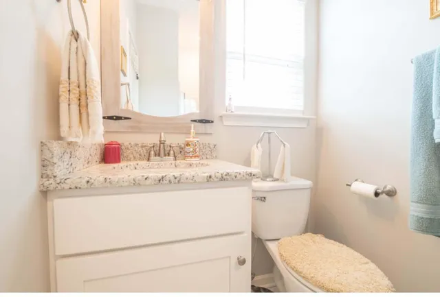a bathroom with a granite countertop toilet sink and mirror