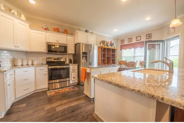 a kitchen with stainless steel appliances granite countertop a stove a sink and a refrigerator