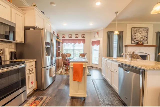a kitchen with stainless steel appliances granite countertop a refrigerator a stove top oven a sink dishwasher and wooden cabinets with wooden floor