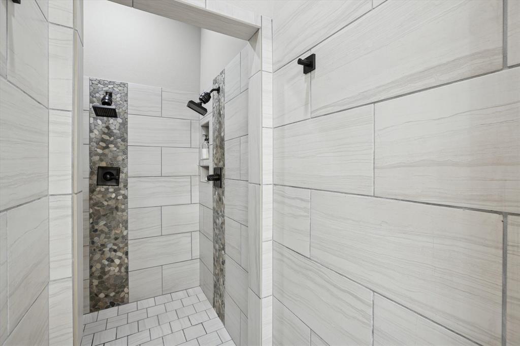 542 Pierce Road Red Oak, TX 75154 - Photo 16 of 27 Walk-in shower featuring light-toned rectangular tile walls and a mosaic pebble accent strip