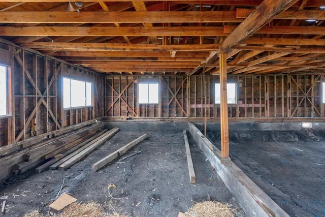 a view of an empty room with wooden floor and windows