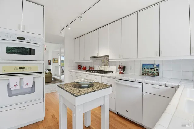 a kitchen with granite countertop white cabinets and white appliances