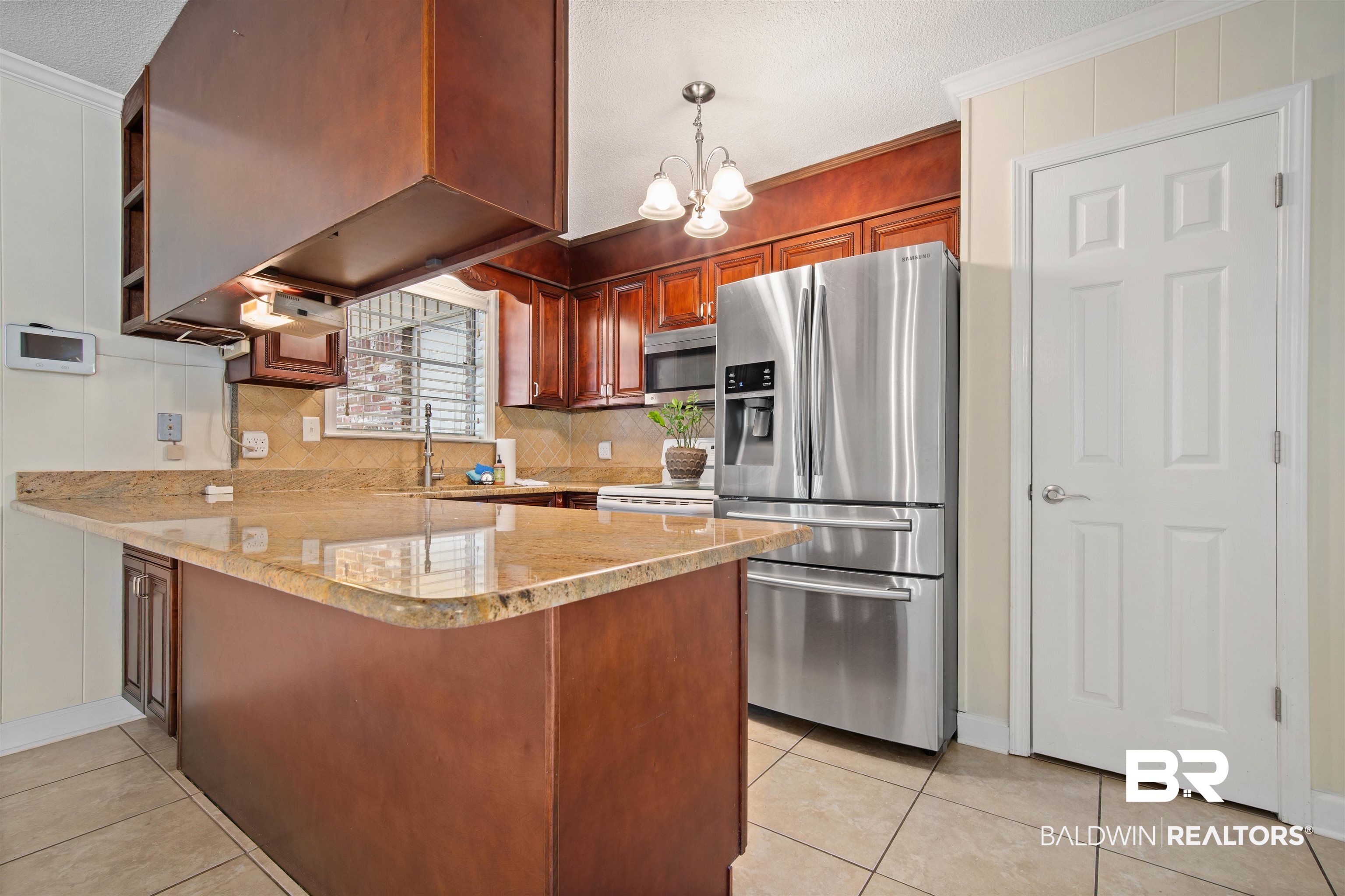 1325 Pawnee Circle Saraland, AL 36571 - Photo 8 of 26 Kitchen with stainless steel appliances, a peninsula, light tile patterned floors, backsplash, and a textured ceiling