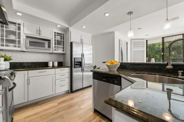 a kitchen with stainless steel appliances granite countertop a sink and a stove