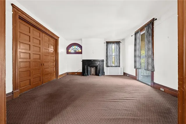 a view of an empty room with a fireplace and a window