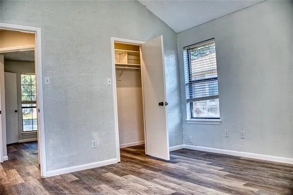 an empty room with wooden floor closet and windows