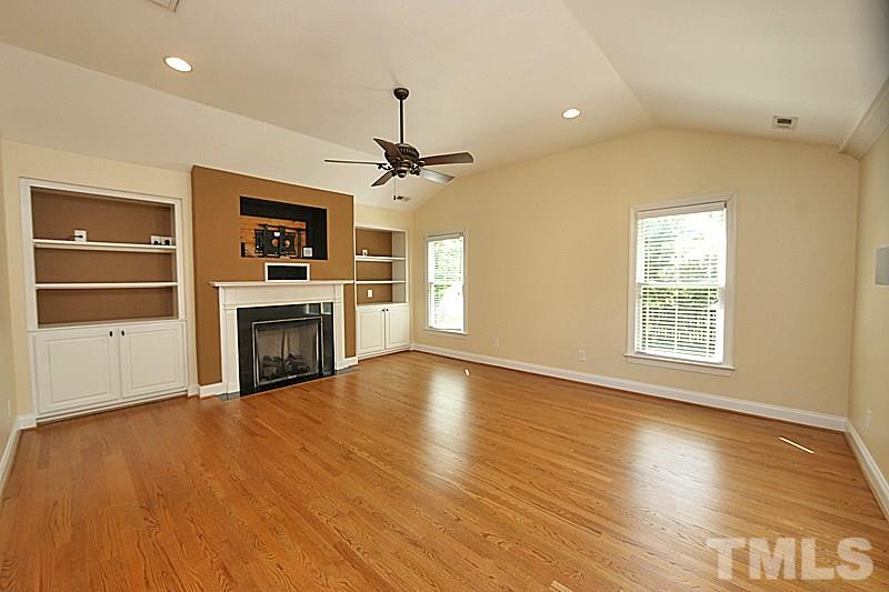 4605 Pitt Street Raleigh, NC 27609 - Photo 11 of 22 an empty room with wooden floor fireplace and windows