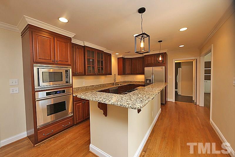 4605 Pitt Street Raleigh, NC 27609 - Photo 8 of 22 a kitchen with granite countertop wooden cabinets and stainless steel appliances