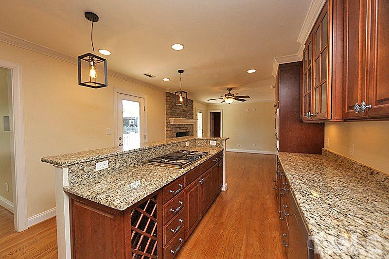 4605 Pitt Street Raleigh, NC 27609 - Photo 9 of 22 a kitchen with kitchen island granite countertop a stove and a wooden floor