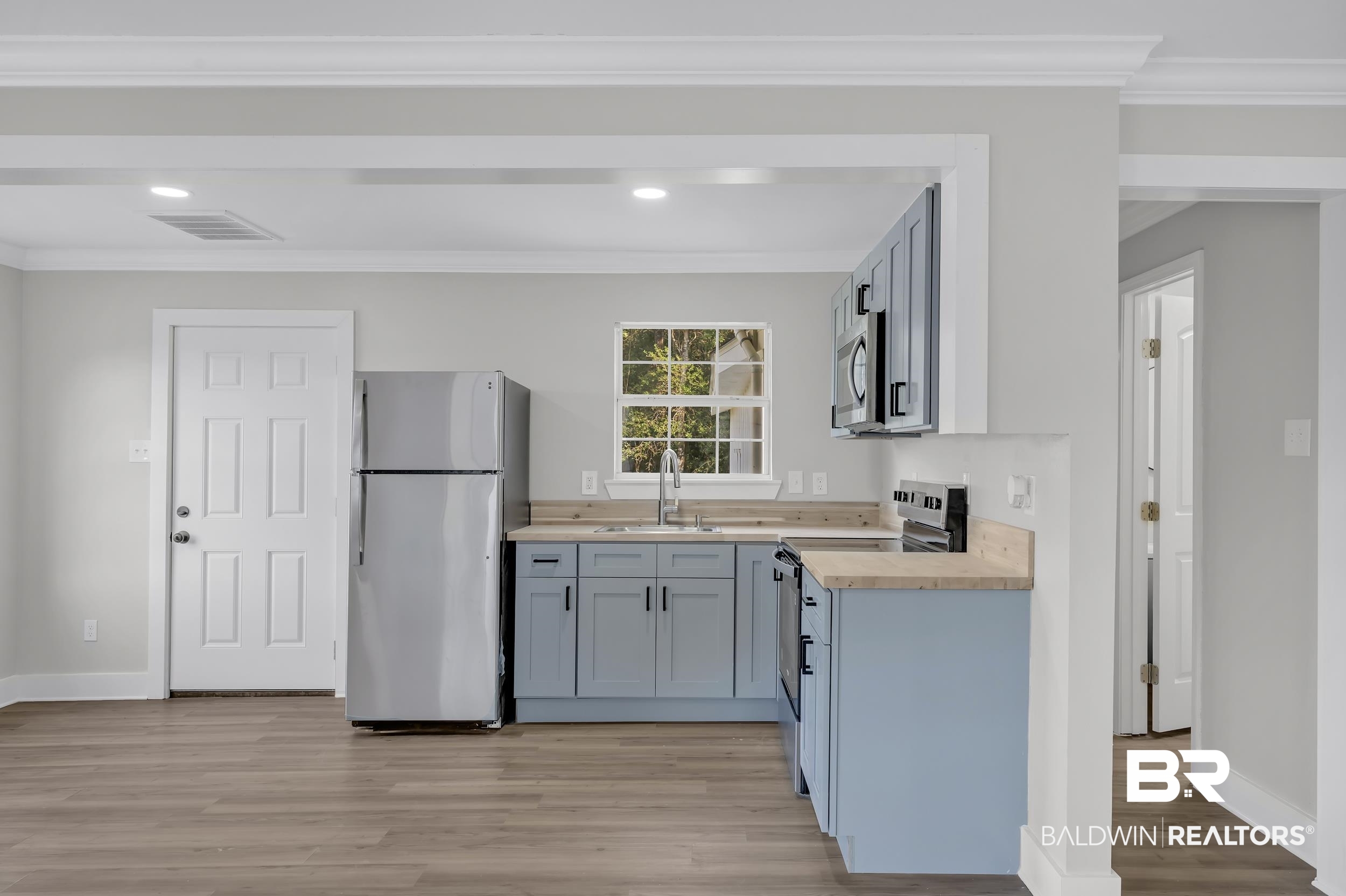 8351 Theodore Dawes Road Theodore, AL 36582 - Photo 33 of 46 Kitchen featuring stainless steel appliances, ornamental molding, light wood finished floors, butcher block counters, and gray cabinetry