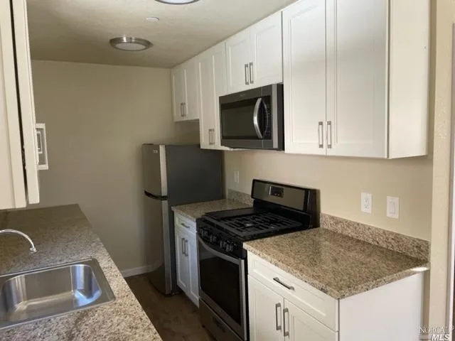 a kitchen with granite countertop a sink stove and microwave