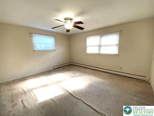an empty room with windows and chandelier fan