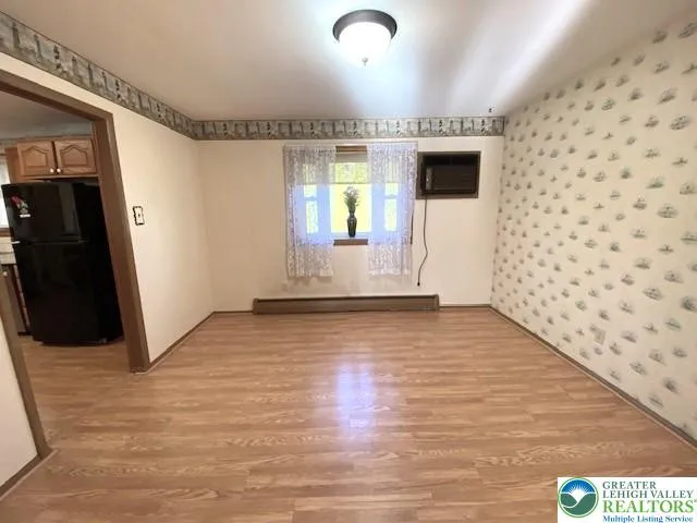 a view of a hallway with wooden floor and a refrigerator