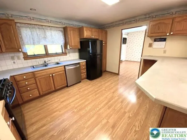 a kitchen with stainless steel appliances granite countertop a refrigerator a sink dishwasher and wooden cabinets with wooden floor