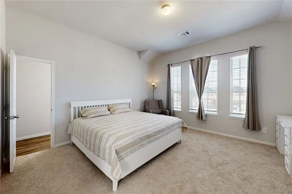 a bedroom with a bed lamp and windows