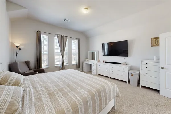 a bedroom with a bed and a flat tv screen on dresser