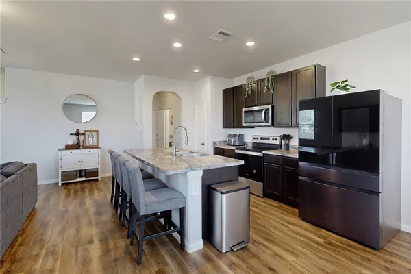 a kitchen with stainless steel appliances a stove a sink a microwave a refrigerator and cabinets