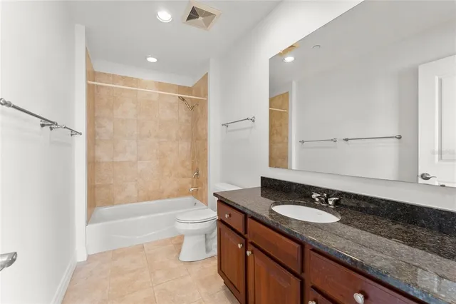 a bathroom with a granite countertop sink a toilet a mirror and shower