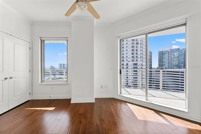 a view of an empty room with wooden floor and a window