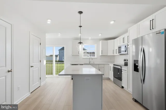 a kitchen with kitchen island a refrigerator stove and sink
