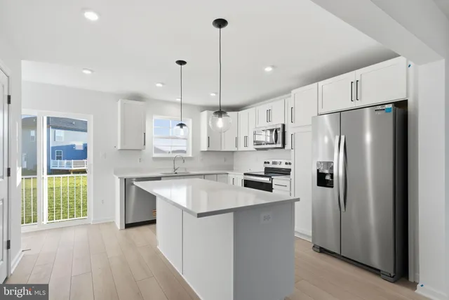 a kitchen with stainless steel appliances granite countertop a refrigerator a sink dishwasher a stove and a refrigerator with wooden floor