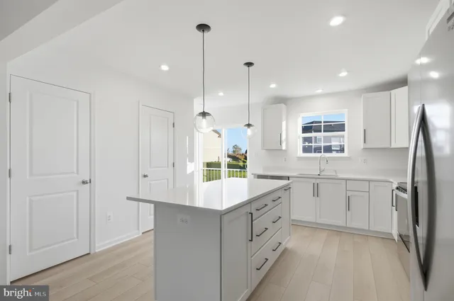 a kitchen with kitchen island white cabinets and refrigerator