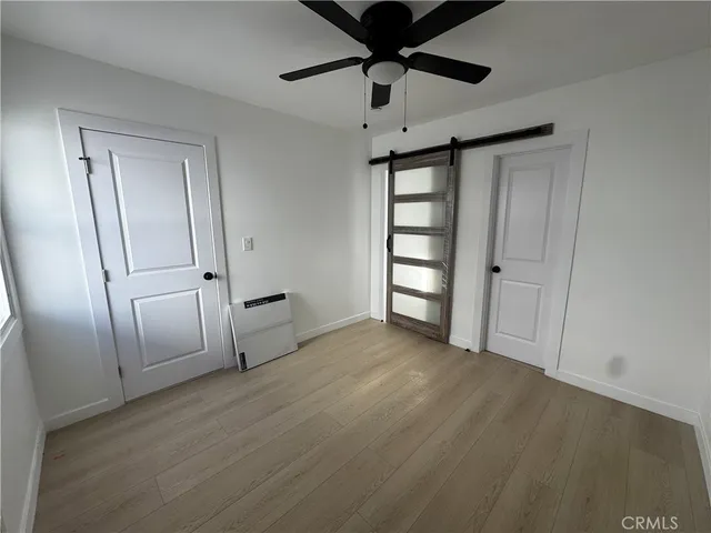 an empty room with wooden floor cabinet and windows