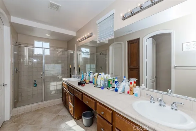 a bathroom with double vanity sinks a shower and a mirror