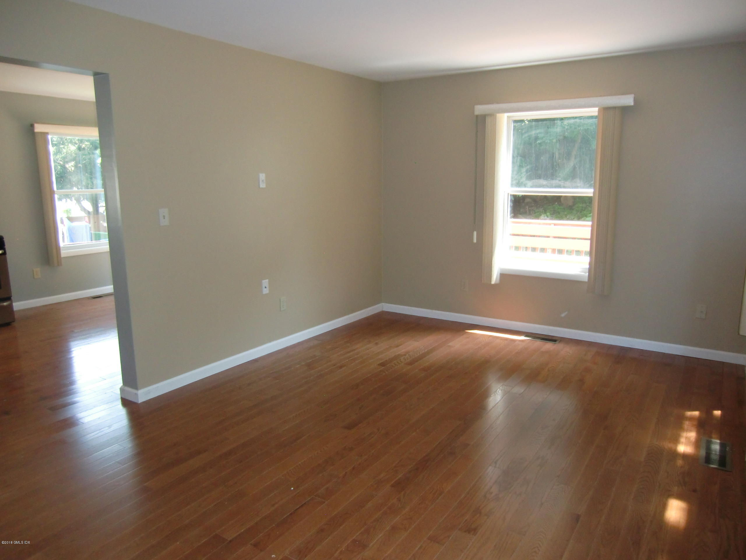 6 Booth Court, Unit B Greenwich, CT 06830 - Photo 3 of 9 a view of an empty room with wooden floor and a window