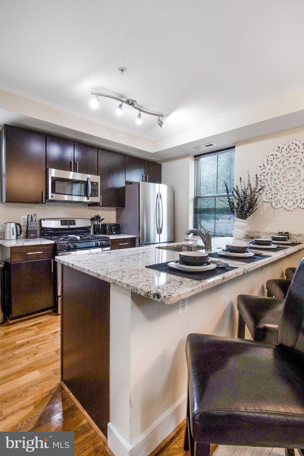 417 18th Street Northeast, Unit 101 Washington, DC 20002 - Photo 36 of 57 a kitchen with stainless steel appliances granite countertop a stove a sink and a microwave