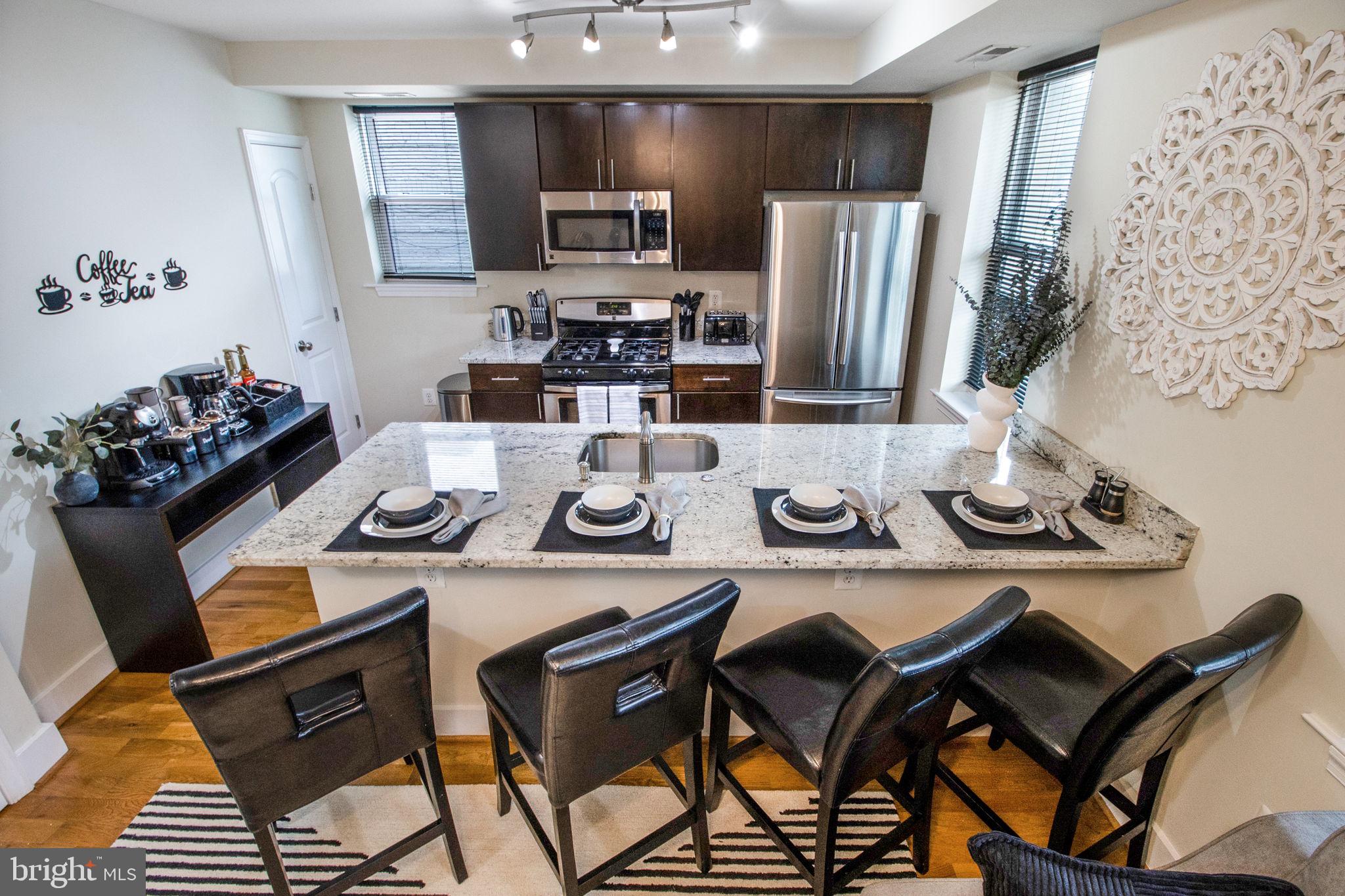 417 18th Street Northeast, Unit 101 Washington, DC 20002 - Photo 37 of 57 a kitchen with stainless steel appliances kitchen island granite countertop a dining table and chairs