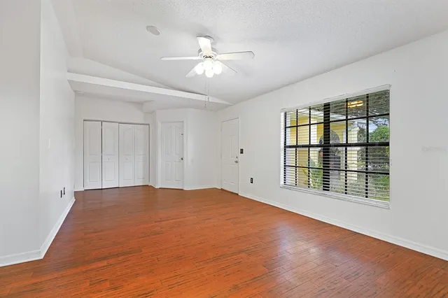 a view of empty room with wooden floor and fan