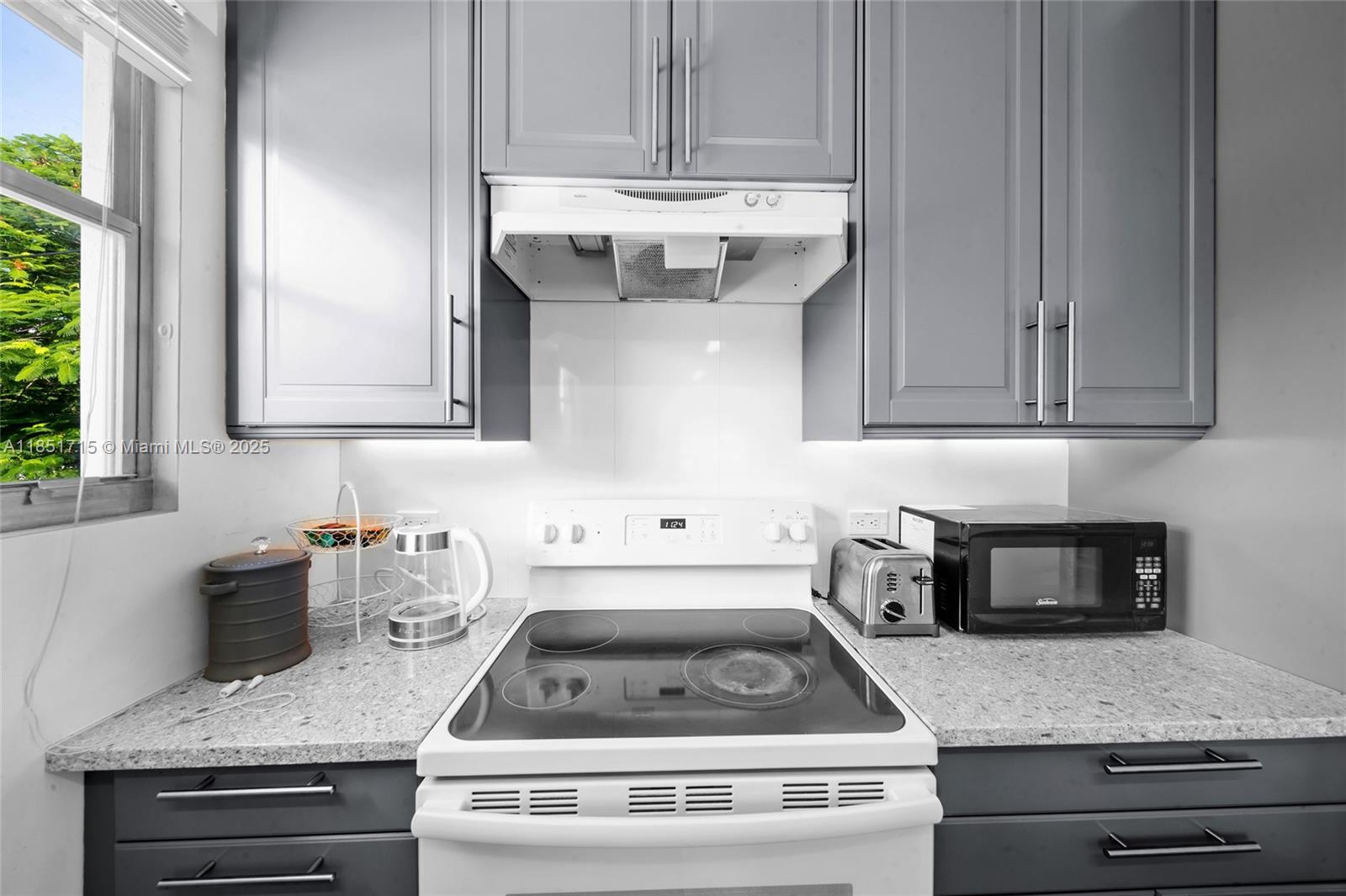 1520 Southwest 11th Terrace, Unit B Miami, FL 33135 - Photo 11 of 32 a kitchen with granite countertop a stove a microwave and cabinets