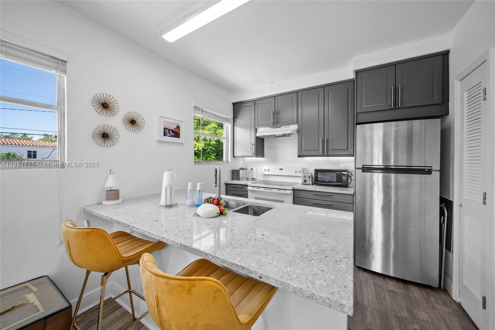 1520 Southwest 11th Terrace, Unit B Miami, FL 33135 - Photo 3 of 32 a kitchen with stainless steel appliances granite countertop a refrigerator a sink a stove and white cabinets with wooden floor