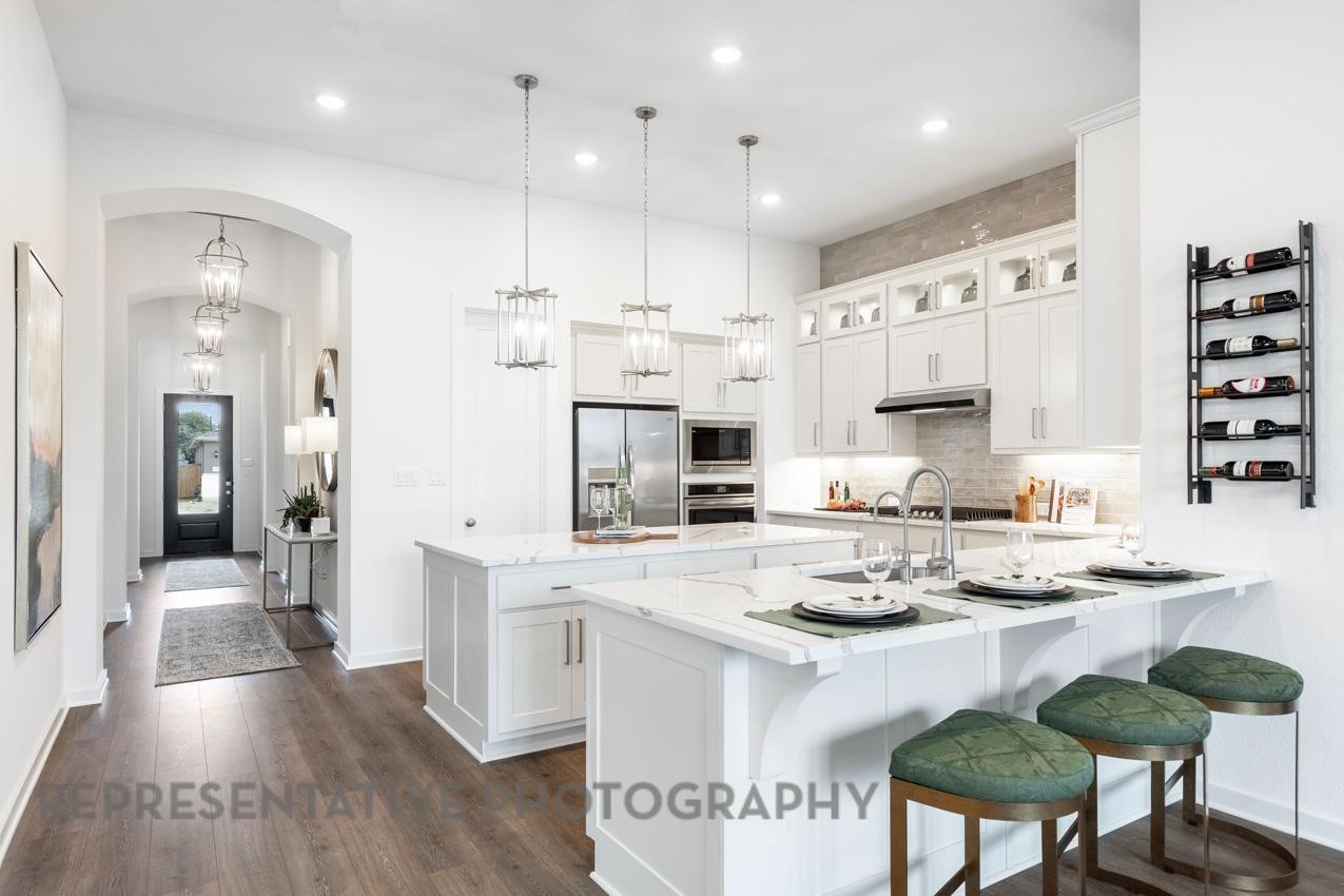 2714 Peach Vly Road Fulshear, TX 77423 - Photo 11 of 47 a kitchen with stainless steel appliances kitchen island granite countertop a sink a stove a refrigerator and white cabinets